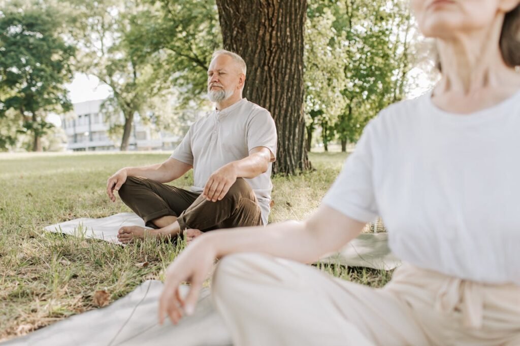 A quiet outdoor scene, with a middle aged couple practicing Yoga. Representing midlife mental wellbeing.