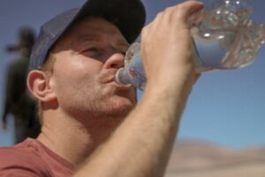 A man drinking a bottle of water to stay hydrated